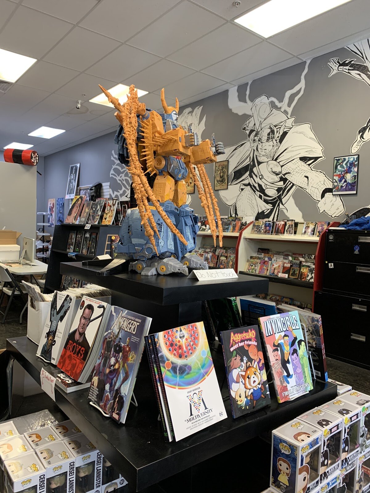 Large robotic figure stands over display of graphic novels