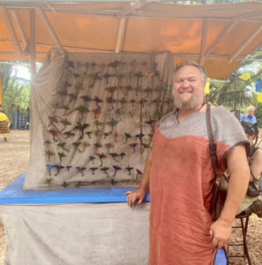 Leatherworker in front of display of leather dragon hair clips and pins