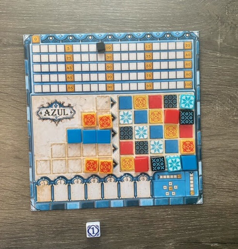 Pictured: a colorful Azul player card, with some tiles placed atop the card and filled in.