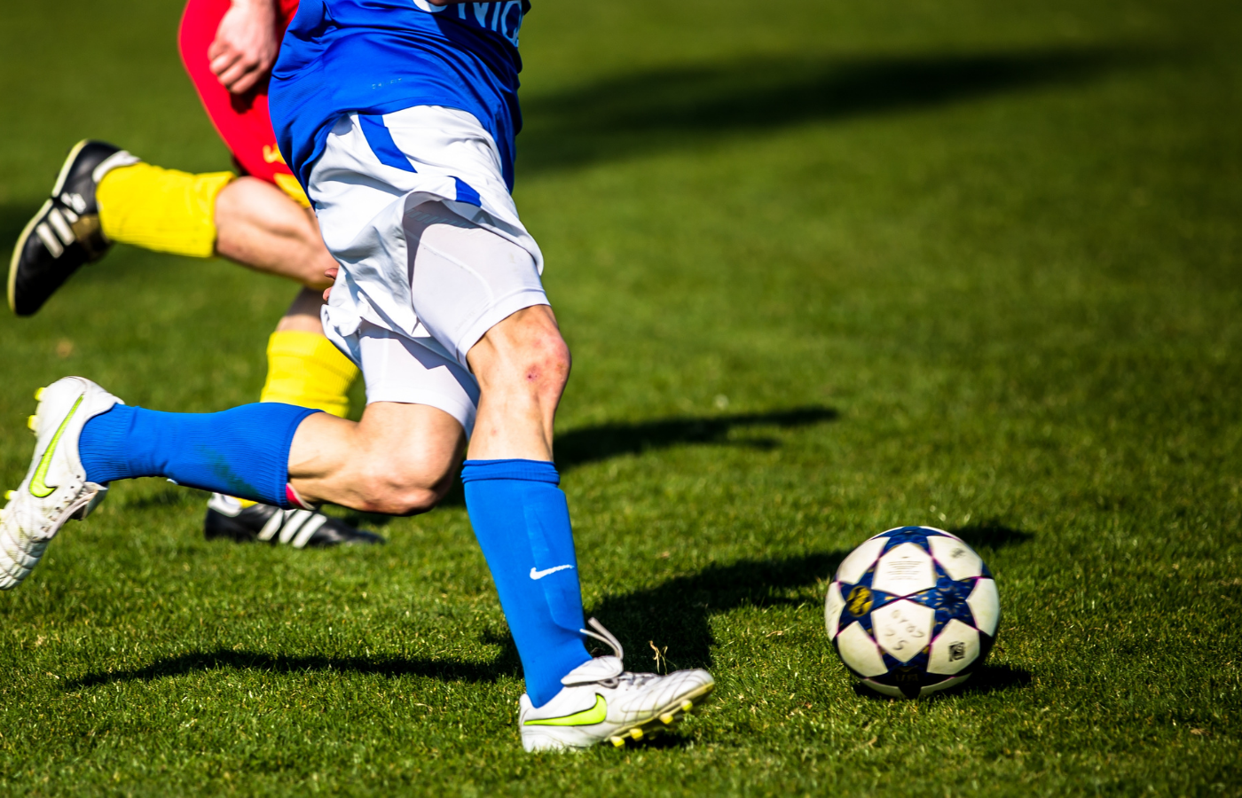 Two sets of legs chasing a soccer ball