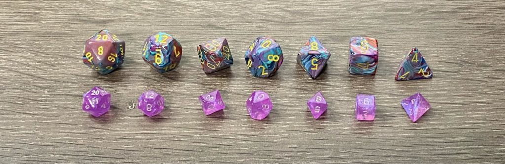 Two polyhedral dice sets laid out largest to smallest