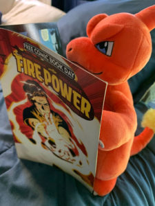 Stuffed Charmander reading a Free Power comic book