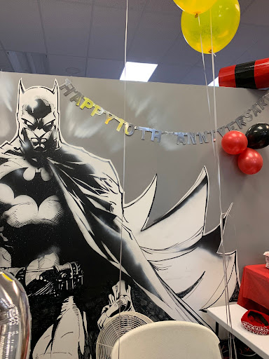 Wall with a cut out of batman on it with a silver and gold happy tenth anniversary sign