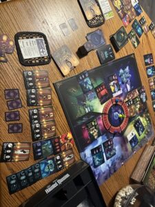 The Haunted Mansion Call of Spirits Game fully spread out on a table, including the game board, meeples and cards from the game.